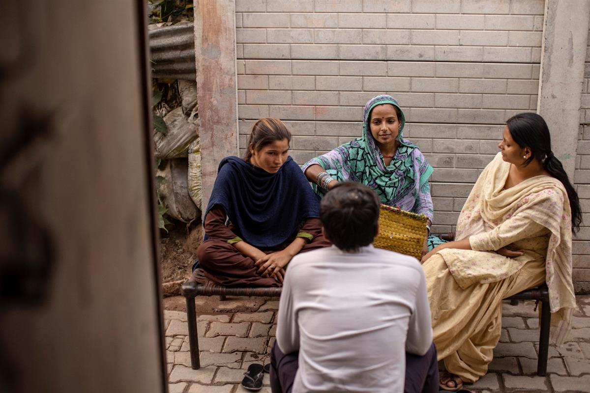 Tre asiatiske kvinner i konsentrert samtale med en mann, som sitter med ryggen til. Foto: Getty Images