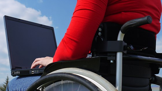 Person i rullestol som skriver på PC