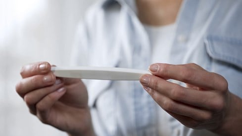 Kvinne holder graviditetstest i hendene