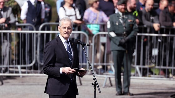 Statsminister Jonas Gahr Støre på Festplassen på Akershus festning. Står ved en mikrofon og holder tale for dagen.