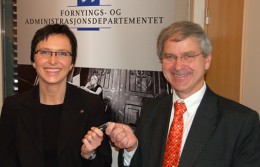 Bilde: Standardiseringsrådets leder Olaf Østensen overleverer forslaget til statsråd Heidi Grande Røys på en minnepinnne. Foto: FAD