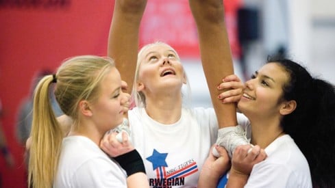 Foto: Johnny Syversen Tre cheerleading-jenter står i base og holder en fjerde jente som vi bare ser beina til.