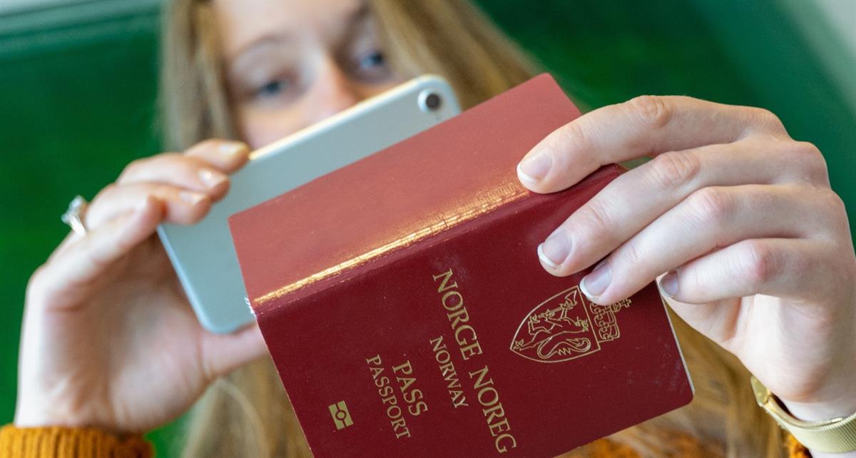Woman taking a picture of her passport with a mobile phone.