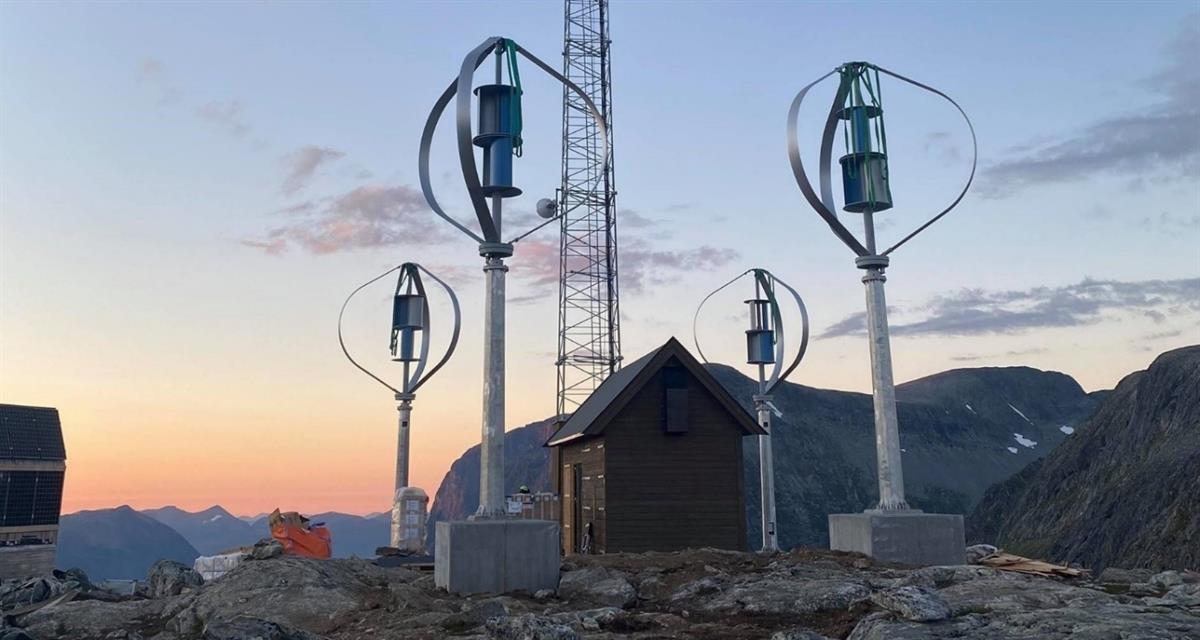 Telia's base station at Trollstigen. In the foreground is the base station with solar panels and windmills for power. Mountain landscape in the background.