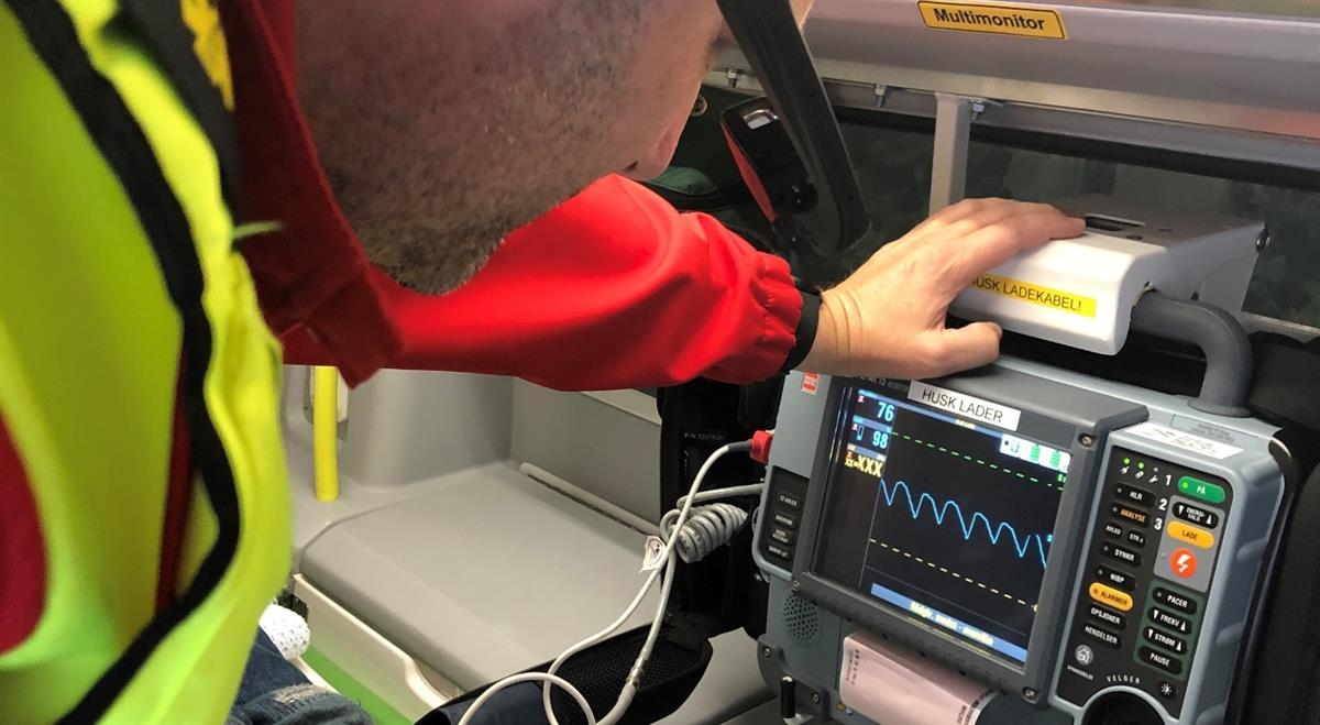 Paramedic looking at vital measurements from a patient in an ambulance.