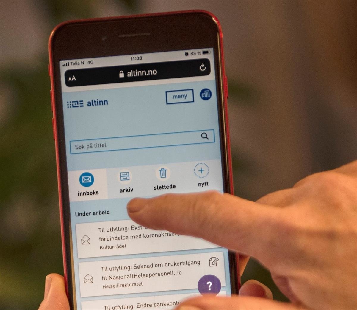 Mobil med Altinn si nettside slått opp. Sida viser blant anna skjema for søknadar knytt til koronasituasjonen.