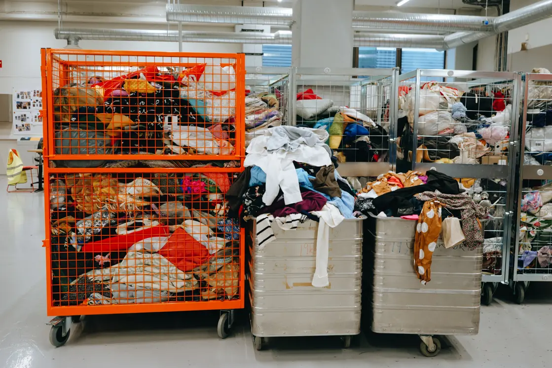 Klær i store beholdere på gjenbruksstasjon.