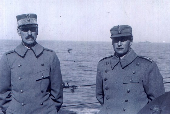 Kong Haakon VII og kronprins Olav står på dekket på et skip. Hav i bakgrunnen.