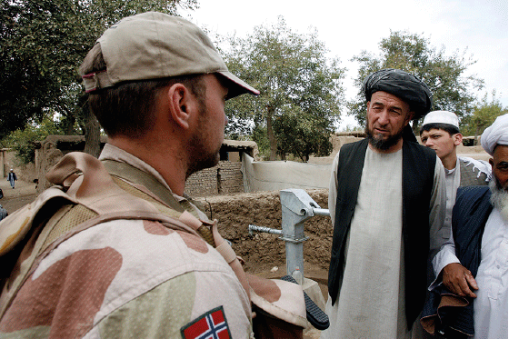 Figur 8.9 Norsk soldat i samtale med lokalbefolkningen. Forventningene lokalt til hva de norske militære styrkene kunne utrette var ofte store. I begynnelsen av innsatsen boret norske styrker brønner for lokalbefolkningen. Slik praksis ble stanset som følge av...