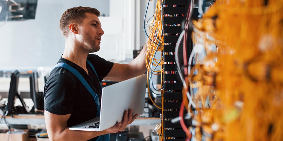 Bilde av en mann som jobber med ledninger på en server.