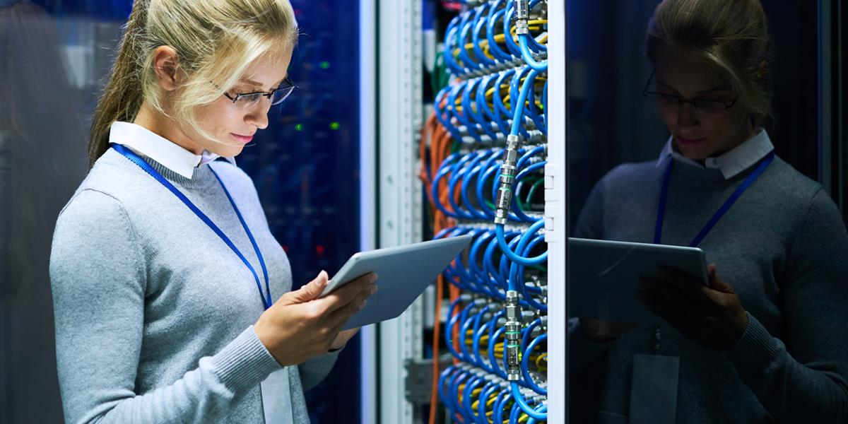 Bilde av en dame i et serverrom som kikker på et nettbrett.
