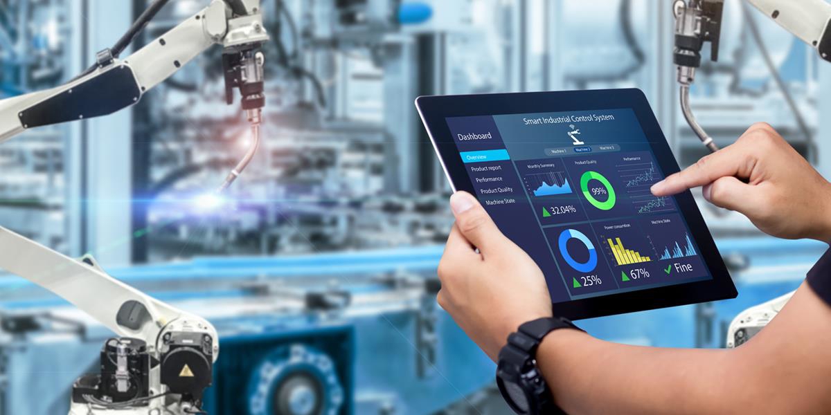 Bilde av hender som holder et nettbrett inne i et fabrikklokale.