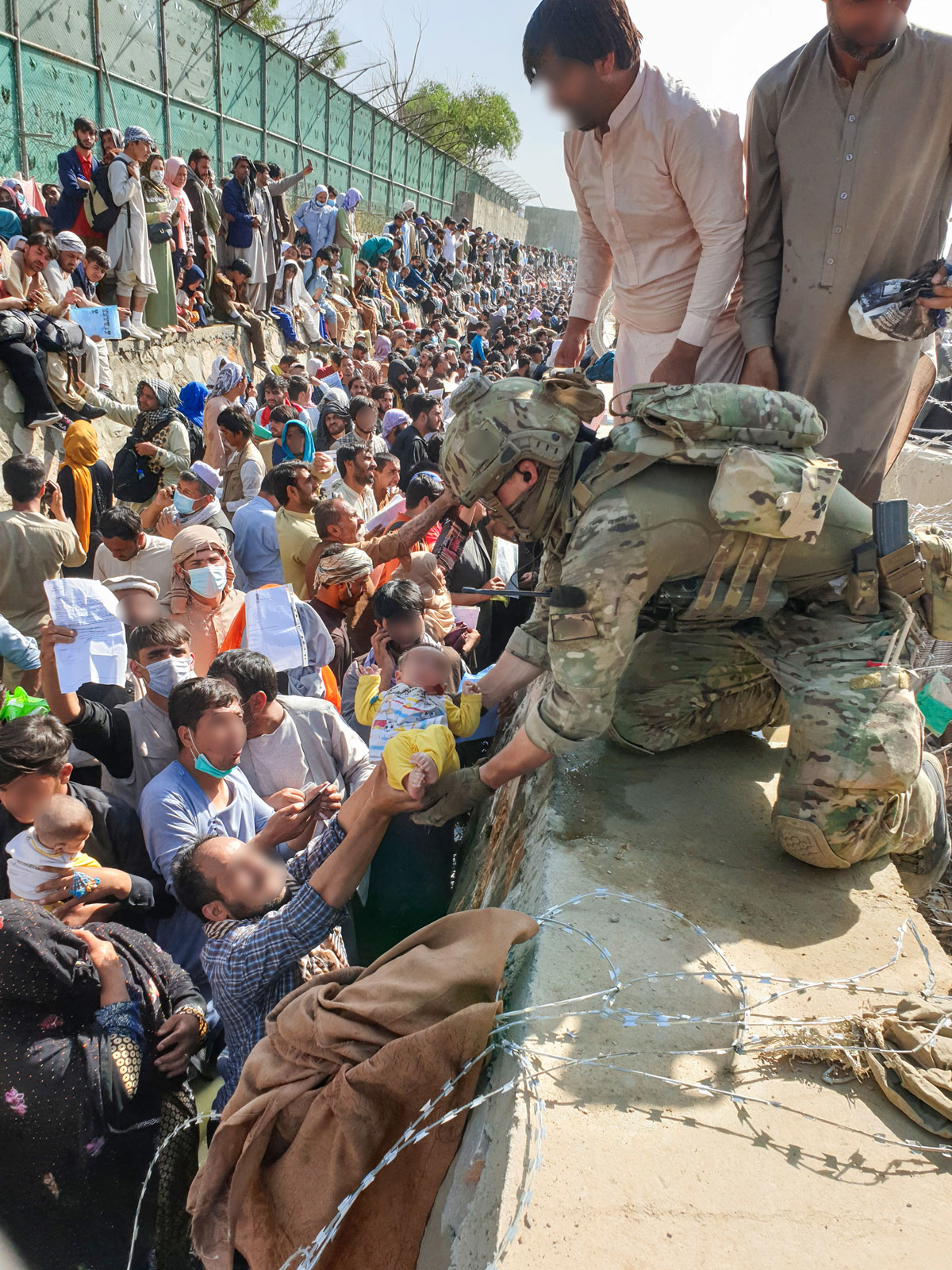 Figur 7.12 En norsk spesialsoldat tar imot et barn som leveres over muren.