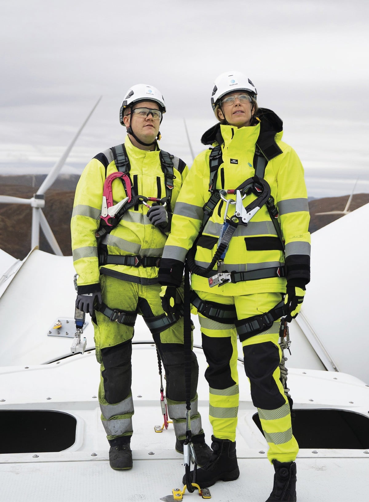 To arbeidere står sikret på toppen av en vindmølle.