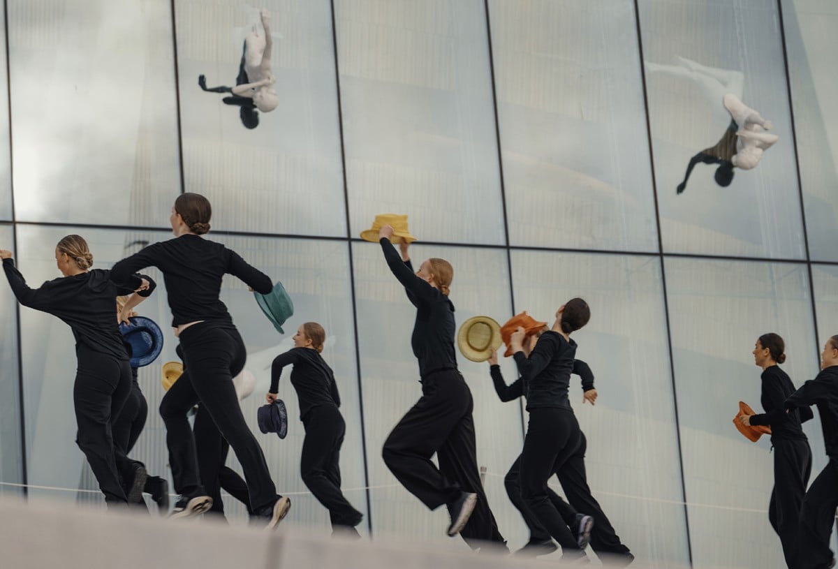 Flere jenter danser foran Operaen i Oslo, kledd i svart med hatter i ulike farger.