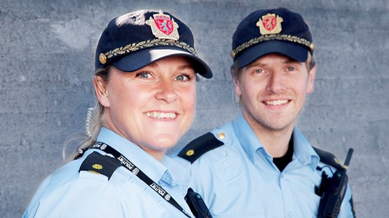 To smilende polititjenestepersoner i uniform