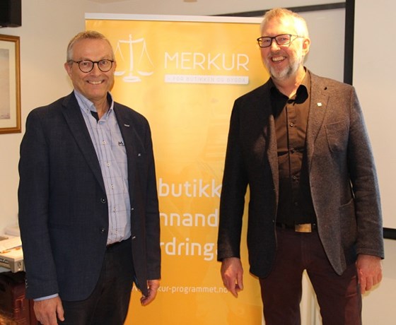 Bilde av Halvor Holmli, direktør for Distriktssenteret og Helge Schei, daglig leder i Merkur-programmet, foran en roll-up med Merkur-programmet sin logo.