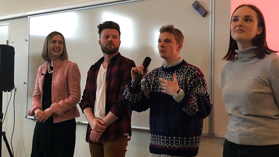 Forsknings- og høyere utdanningsminister Iselin Nybø, lærer Thor Ivar Fløistad og lærerstudentene Markus Teigset og Lillian Ringøen foran en en tavle.