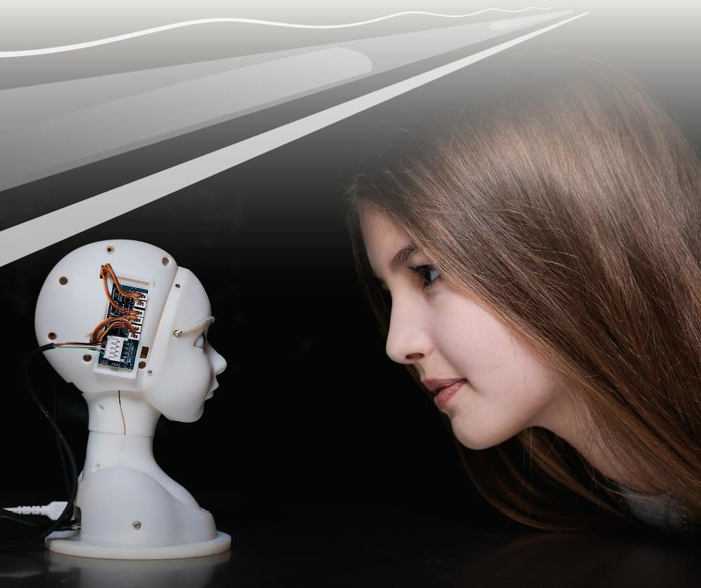SEER: Simulative Emotional Expression Robot by the Japanese artist Takayuki Todo. A young woman looking at a white robot head. Used with permission from Ars Electronica and vog.photo.