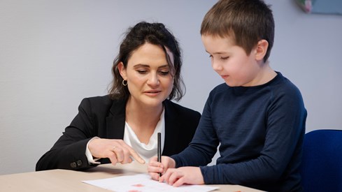 Kunnskapsminister Kari Nessa Nordtun ser på et barn som tegner i barnehagen