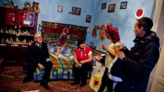Frelsesarmeen-soldat på besøk i hjem hos en fattig familie i Romania