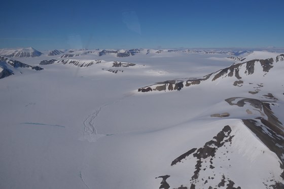 Snødekket landskap av fjell og isbreer på Svalbard.