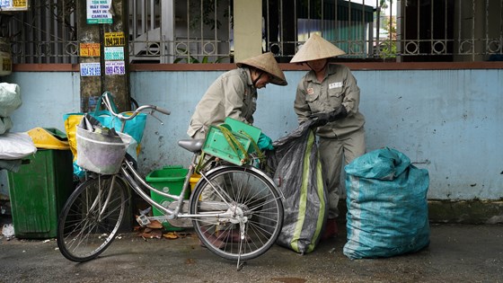 Bilde av to personer som jobber med å løfte søppelsekker