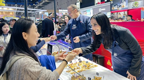 Statssekretær Brekken deler ut brunost på Norges paviljong på den store messen CIIE, i Shanghai.