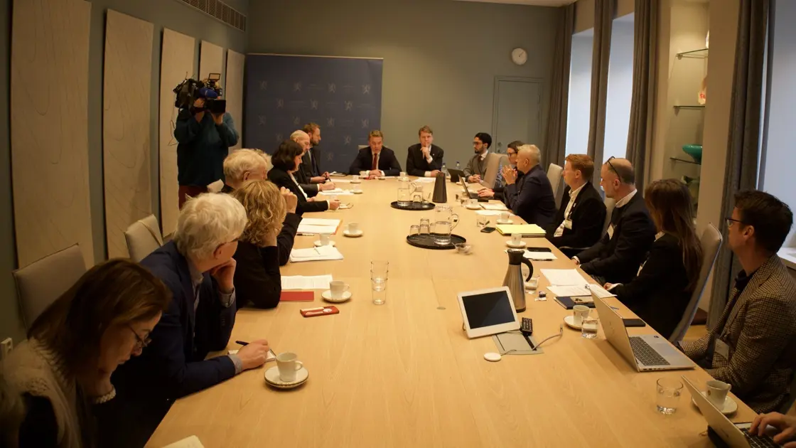 Mennesker som sitter rundt et stort møtebord.