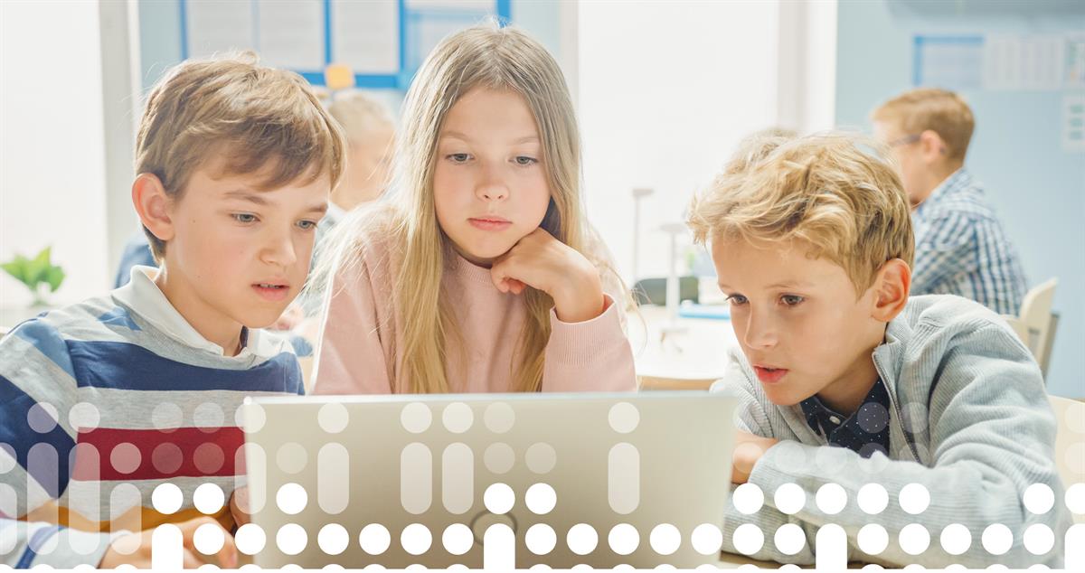 foto av tre barn som arbeider sammen på en bærbar datamaskin i et klasserom