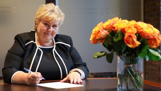 Statsminister Erna Solberg skriver under på regjeringens avskjedssøknad. Sitter ved et bord på Statsministerens kontor.