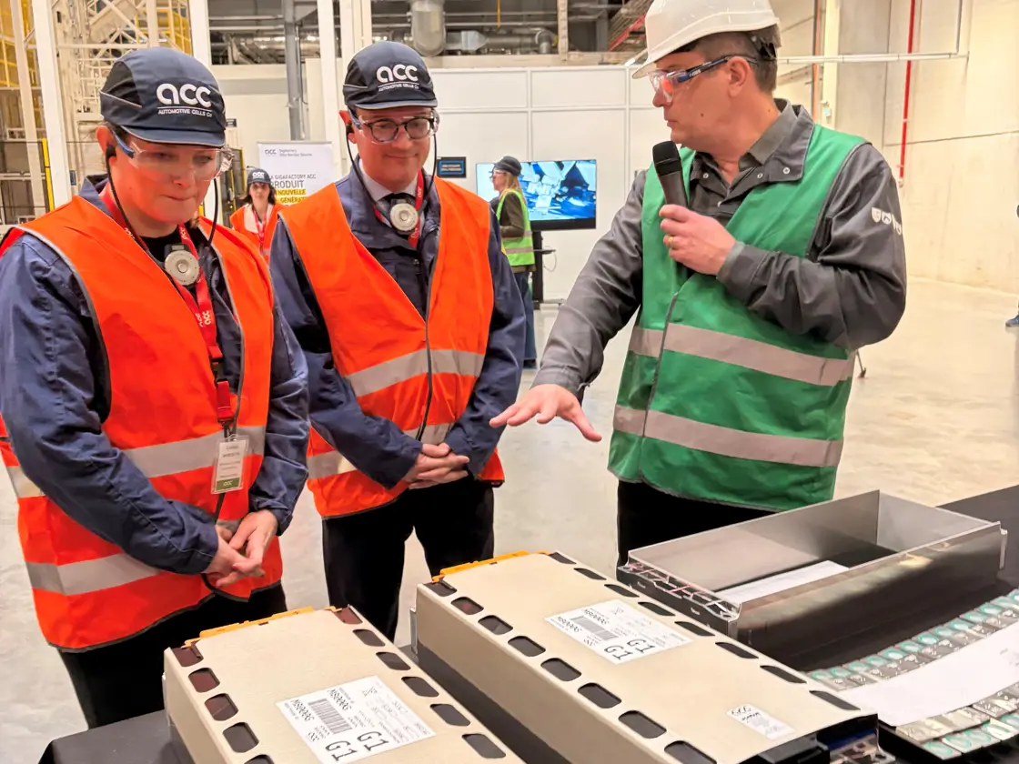 Næringsminister Cecilie Myrseth og den franske industriministeren Sébastien Martin med oransje vest, caps og vernebriller sammen med en ansatt hos fabrikken.
