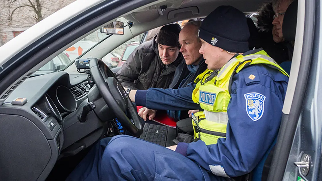 Statsråd Jan Tore Sanner sammen med politiet i en politibil