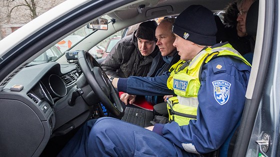 Statsråd Jan Tore Sanner sammen med politiet i en politibil
