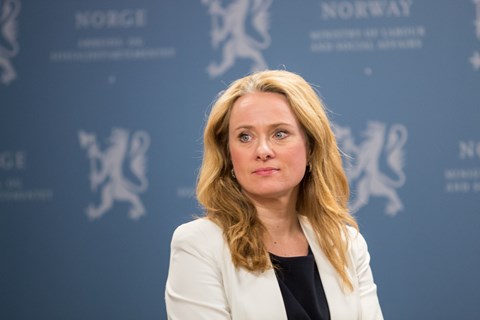 Arbeids- og sosialminister Anniken Hauglie foran blå pressevegg med riksløven.