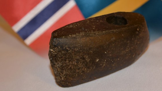Bilde av steinalderøksa med det norske og det svenske flagget i bakgrunnen.