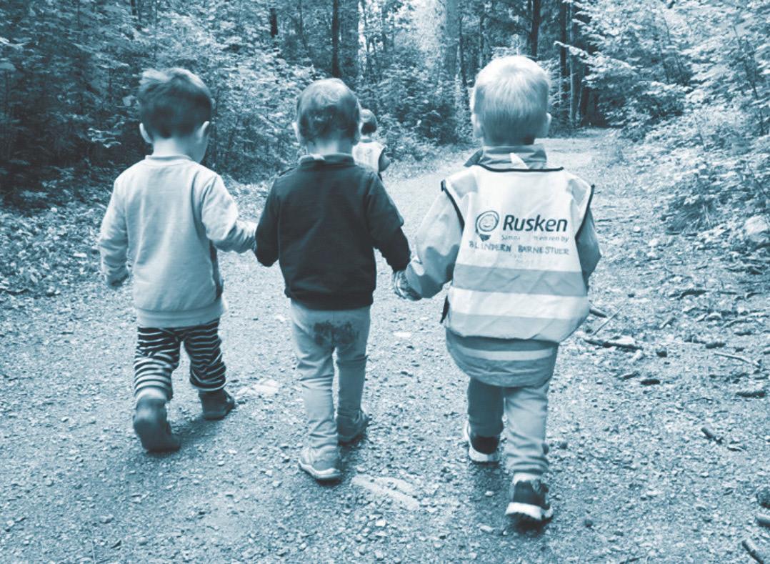 Foto av tre små barn som går tur mens de leier hverandre
