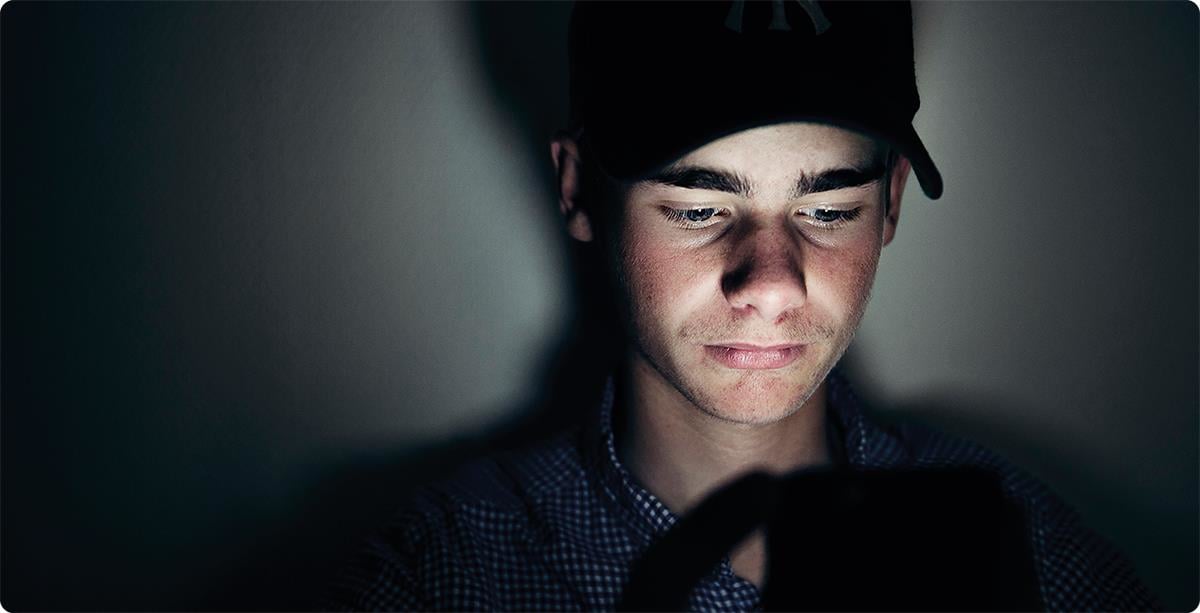 Bekymret gutt med caps ser på mobilen.