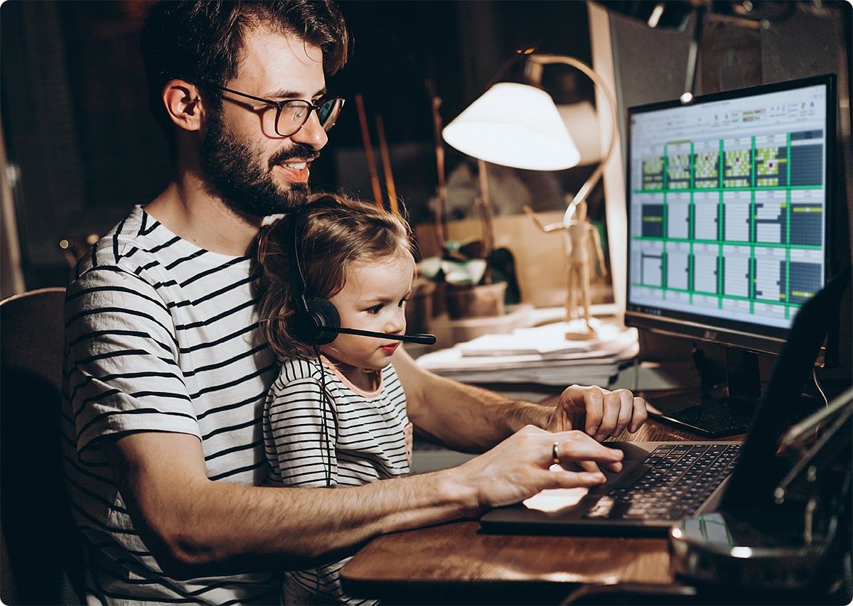 Far jobber på PC med datteren sin på fanget med headset på.