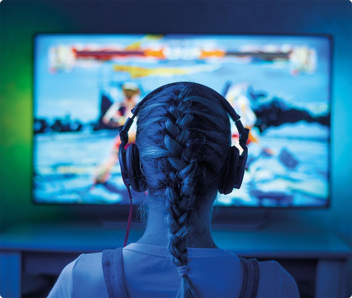 Jente bakfra, med flette og headsett som ser på en stor tv.