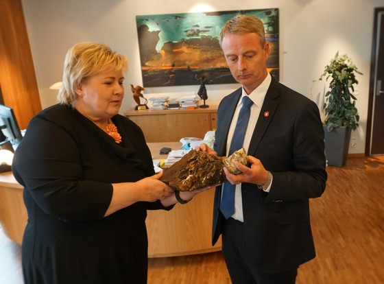 Statsminister Erna Solberg og statsråd Terje Søviknes studerer prøver tatt av Oljedirektoratet i arbeidet med å kartlegge havbunnen. Den store steinen er en såkalt manganskorpe som er skåret ut av en fjernstyrt miniubåt på om lag 1000 meters dyp ved Jan Mayen, den lille er sulfider, hentet opp fra en såkalt svart skorstein på om lag 2000 meters dyp ved Svalbard.