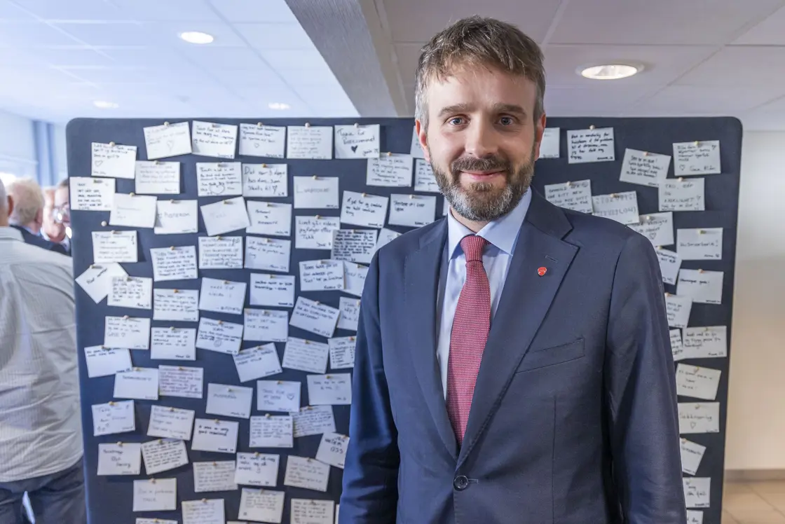 Helse- og omsorgsminister Jan Christian Vestre står foran en vegg med masse lapper, skrevet av gjester på Livslosen
