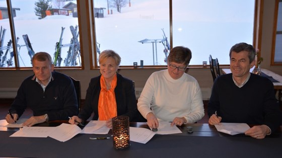 Skipresident Erik Røste, kulturminister Thorhild Widvey, ordfører i Øyer kommune Mari Helene Botterud og styreleder i Alpinco AS Thorvald Sverdrup sitter ved bordet og signerer avtalen om nasjonalanlegg.