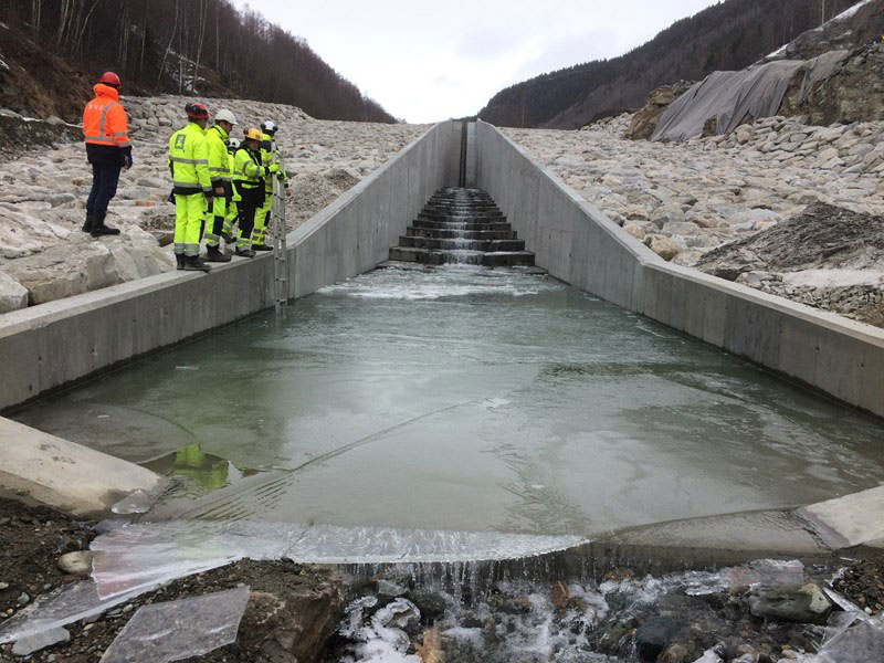 Figur 7.9 Botnlastsperre ved Kvam i Nord-Fron kommune som består av ein damterskel av lausmassar, ein gjennomløpskanal og eit basseng i betong.