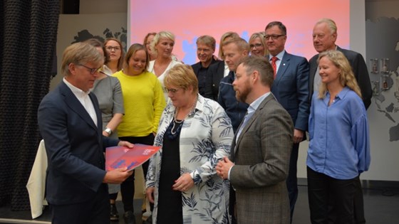Kulturministeren og næringsministeren mottar første innspillsrapport fra rådsleder Reidar Fuglestad. Øvrige medlemmer i rådet står bak de tre.