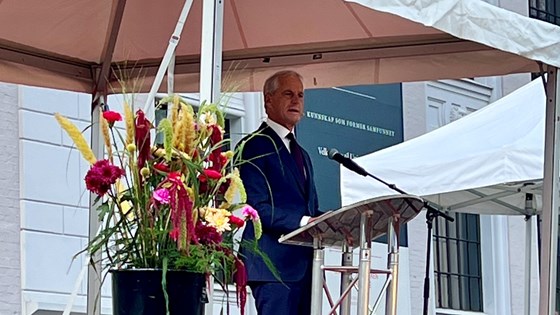 Statsminister Jonas Gahr Støre står bak en talerstol i et telt.