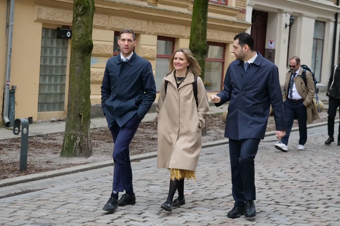 Tre personer går ned en bygate mens de snakker sammen.