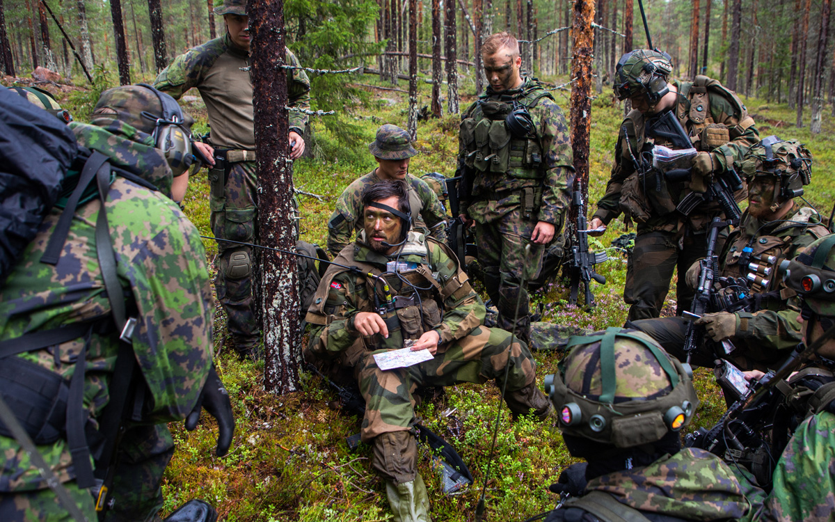 Figur 12.13 Nordiske styrker øver sammen. En troppssjef fra Porsanger bataljon i Finnmark landforsvar gir ordre til norske og finske soldater på øvelse i Nord-Finland i juli 2022.