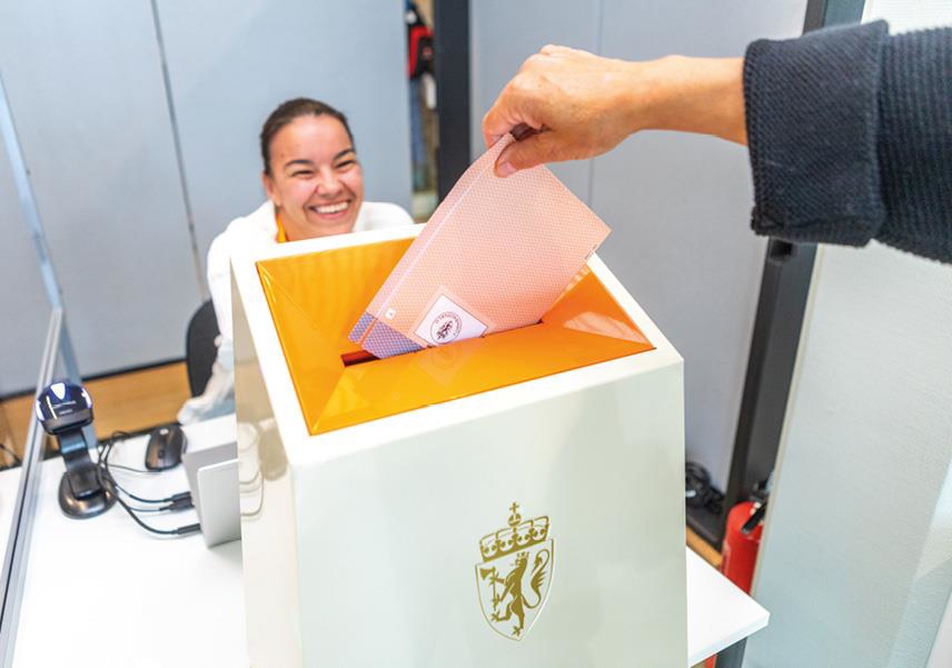 Foto som viser en velgersom legger den stemplede stemmeseddelen rett i urnen.