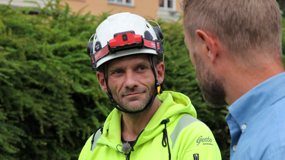 Mann med hjelm ser på helseminister Bent Høie